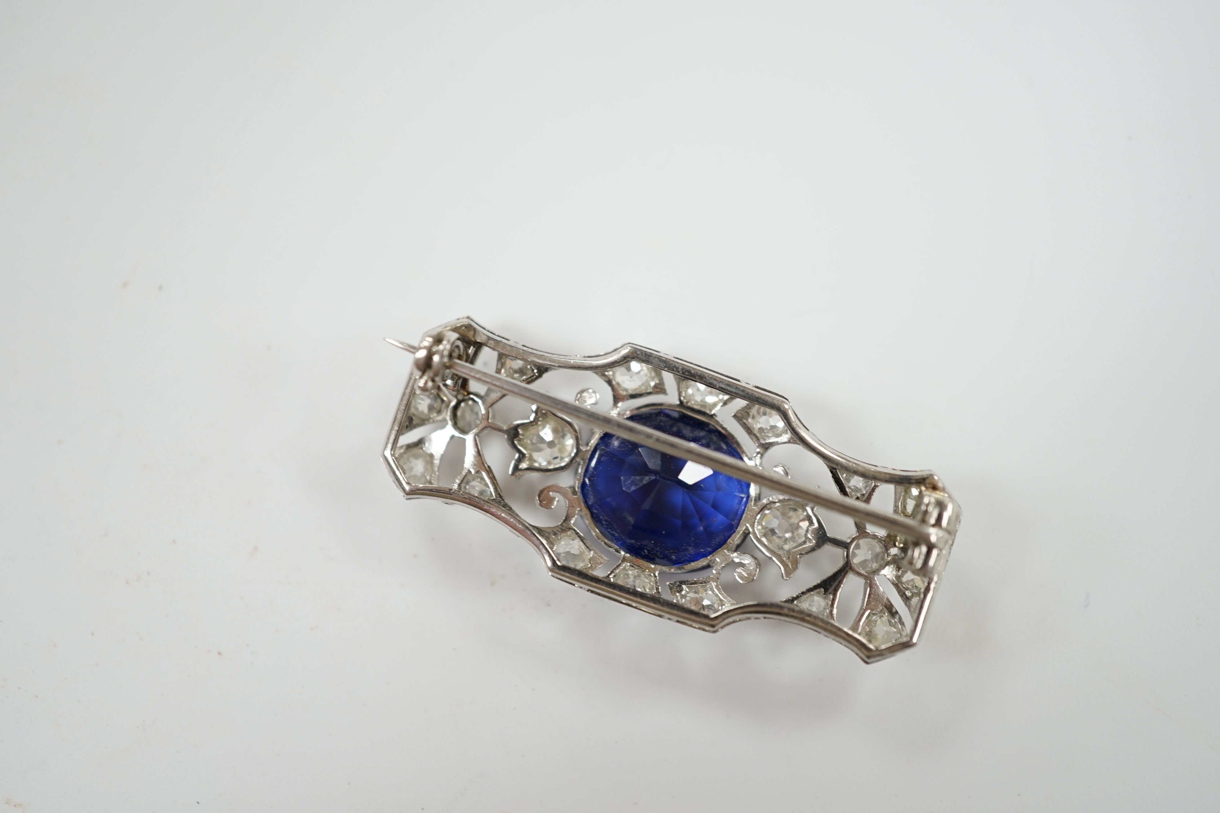 An Art Deco style pierced white metal, single stone synthetic sapphire and diamond cluster set shaped rectangular brooch, 36mm, gross weight 8.1 grams.